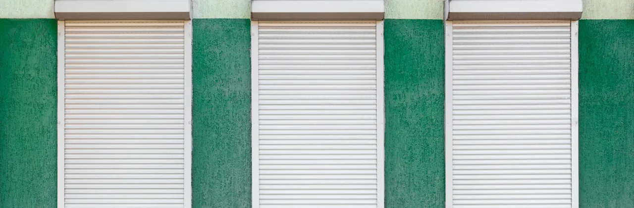 Tres cortinas metálicas cerradas sobre un muro
