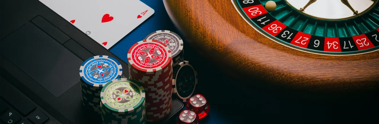 Ruleta, fichas, cartas y dados sobre paño verde oscuro