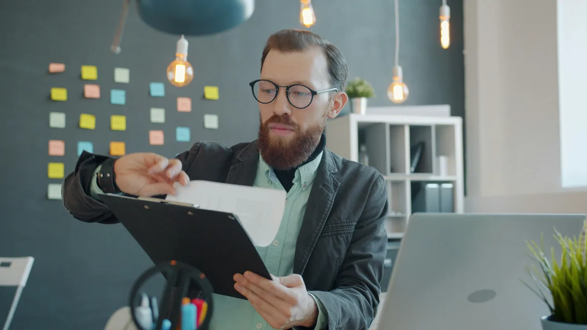 Persona con anteojos leyendo un documento en un escritorio