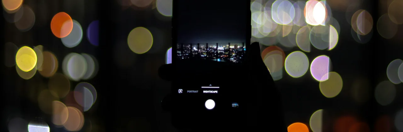 Teléfono sostenido de noche contra luces desenfocadas de colores