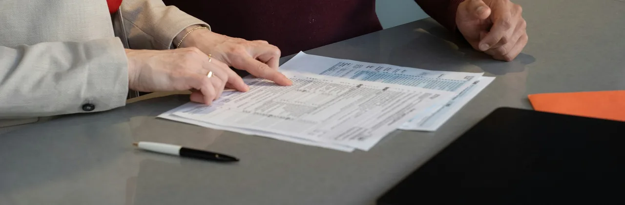 Dos personas revisando un formulario en papel sobre una mesa